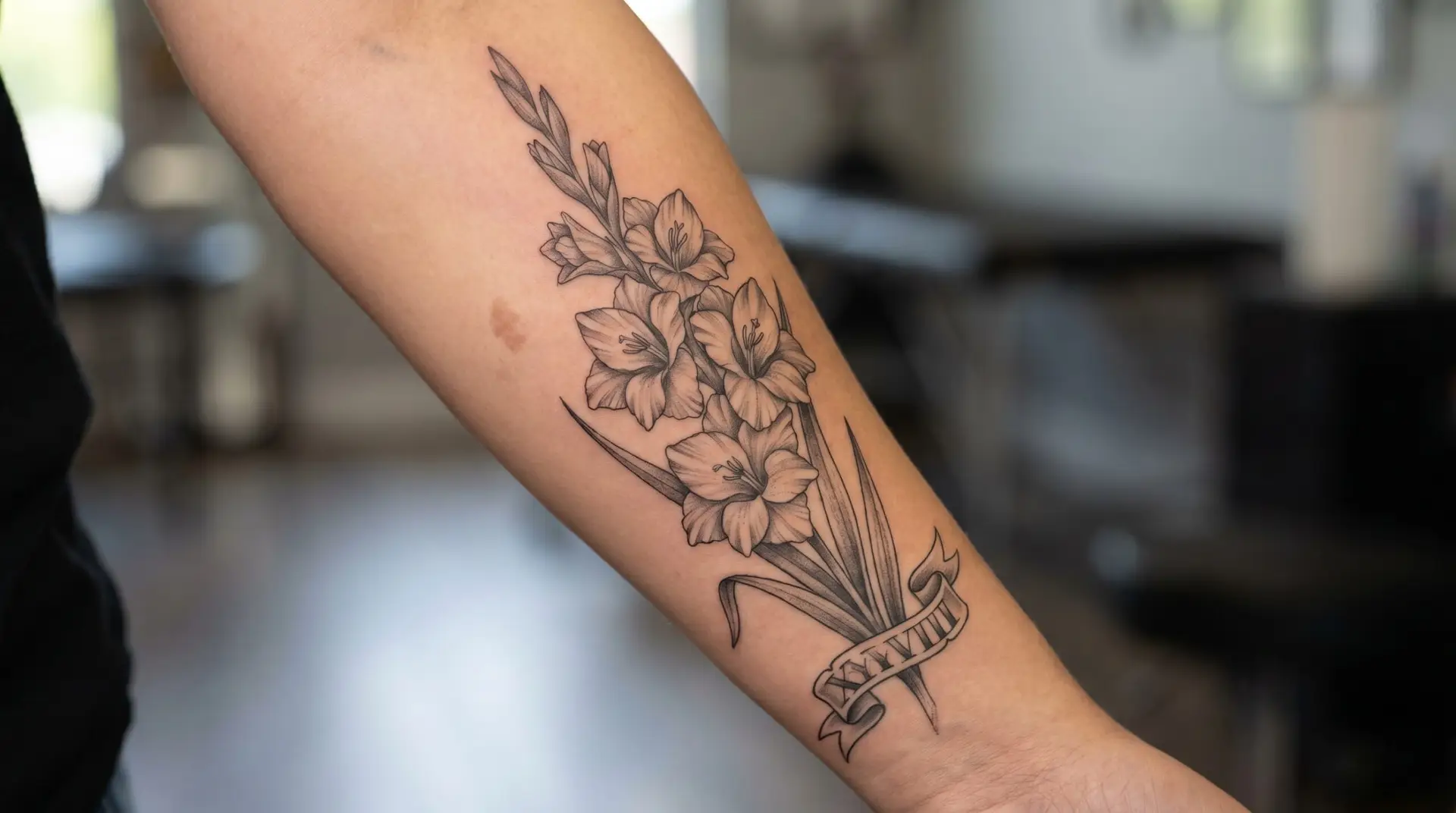 Black-and-grey memorial gladiolus tattoo on forearm with Roman numeral date banner