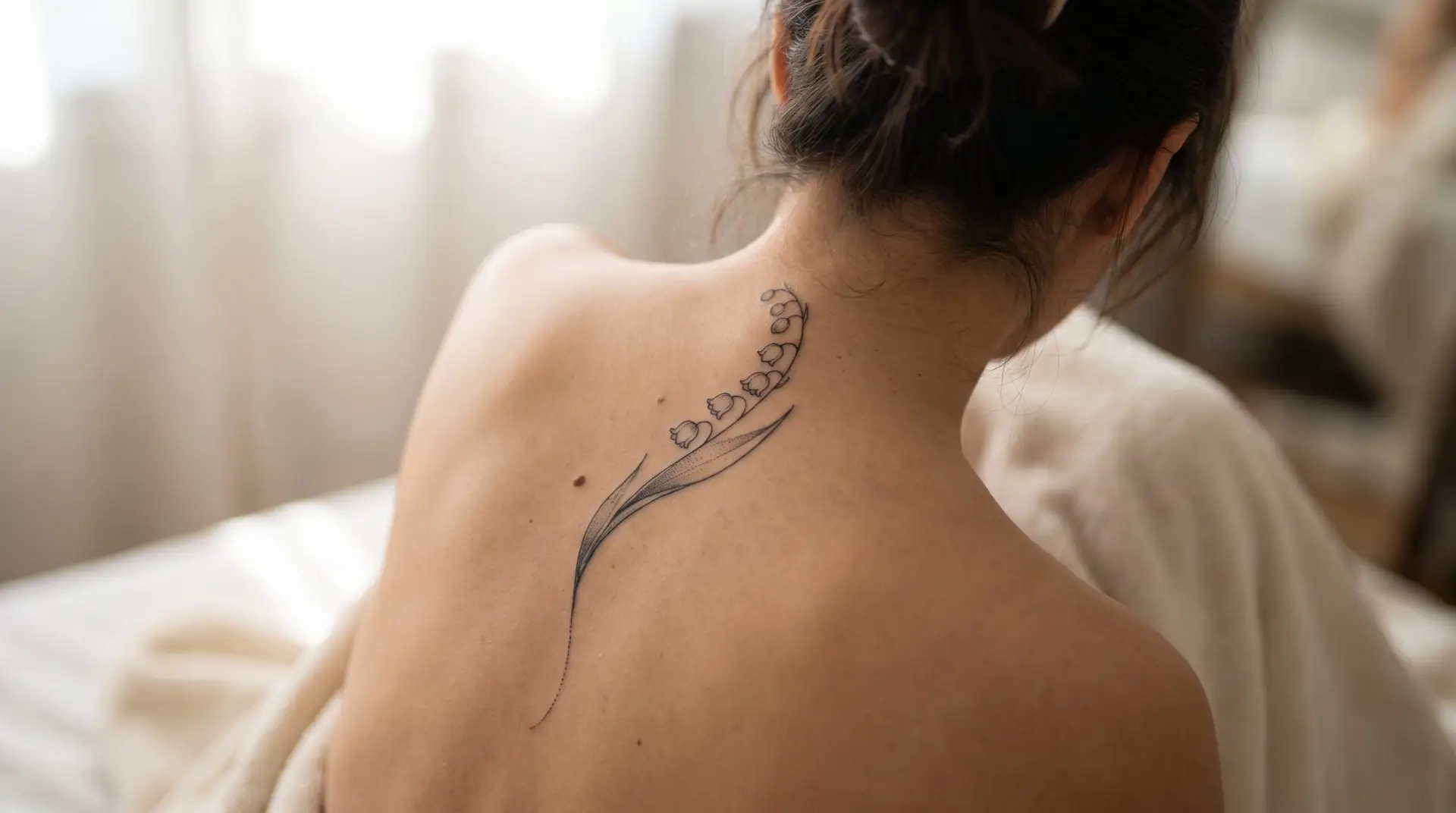 Large lily of the valley tattoo running along spine showing natural curve with arching flower stem