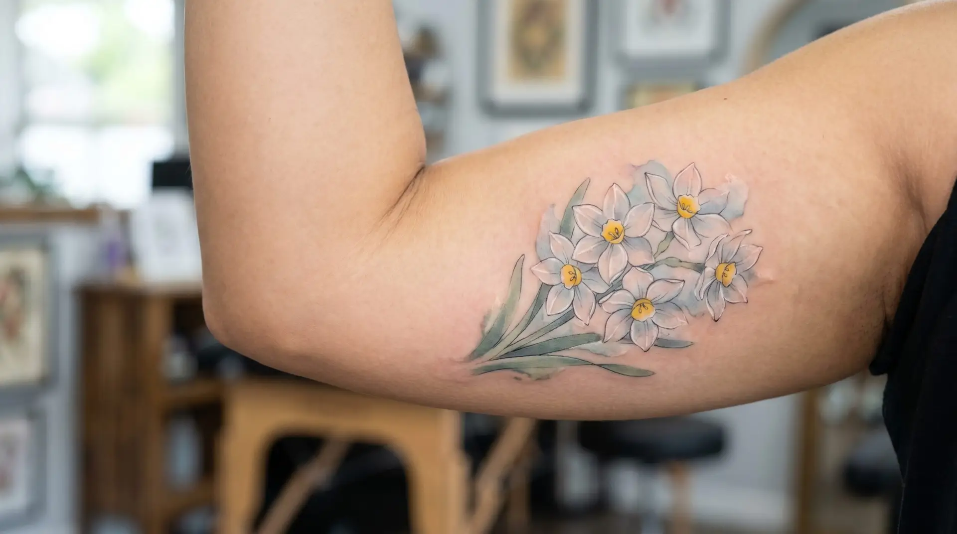 Watercolor white paperwhite narcissus cluster tattoo on inner bicep with cool color bleed
