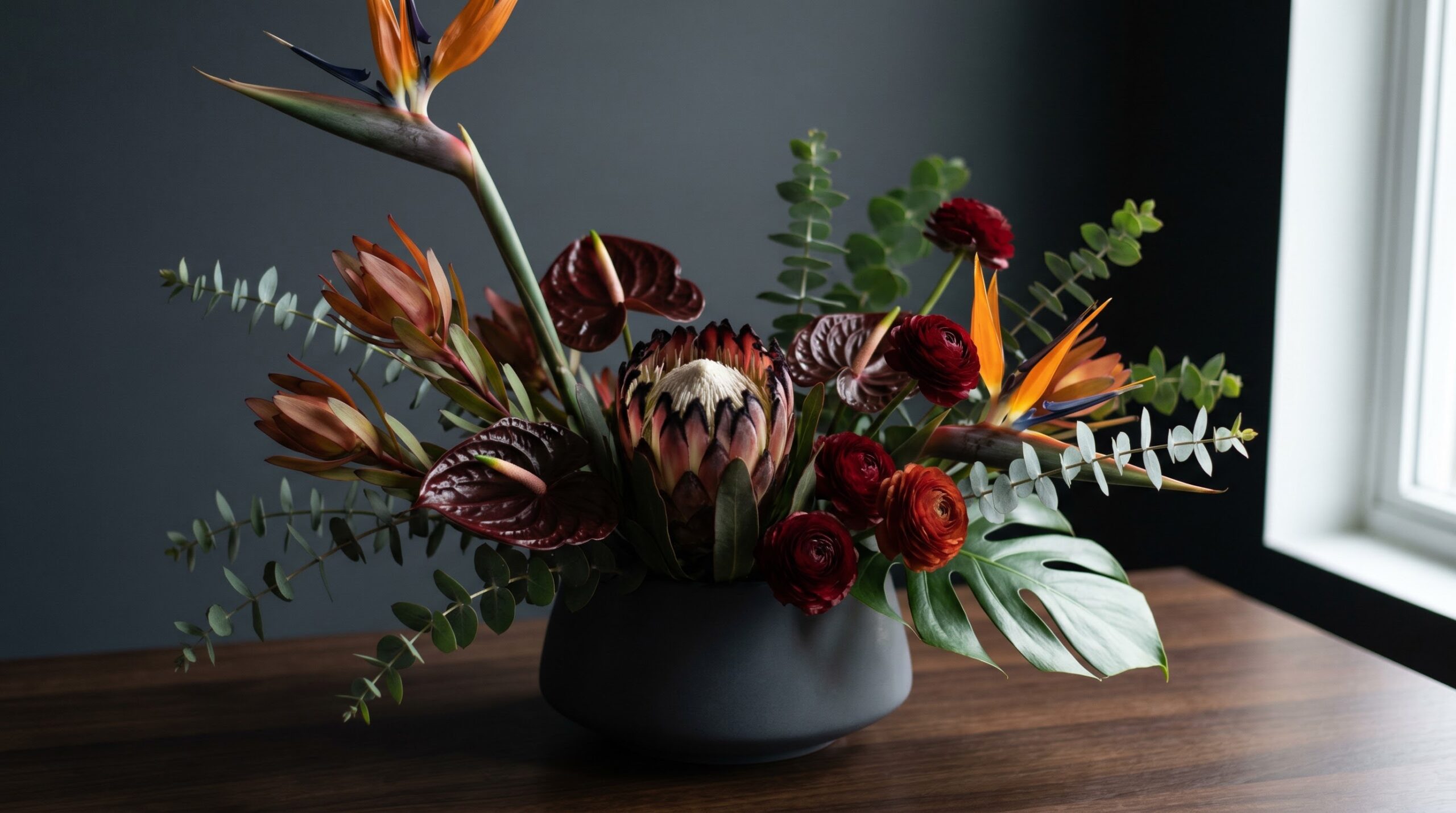 Masculine bouquet of proteas, anthuriums and tropical greens in dark saturated colors