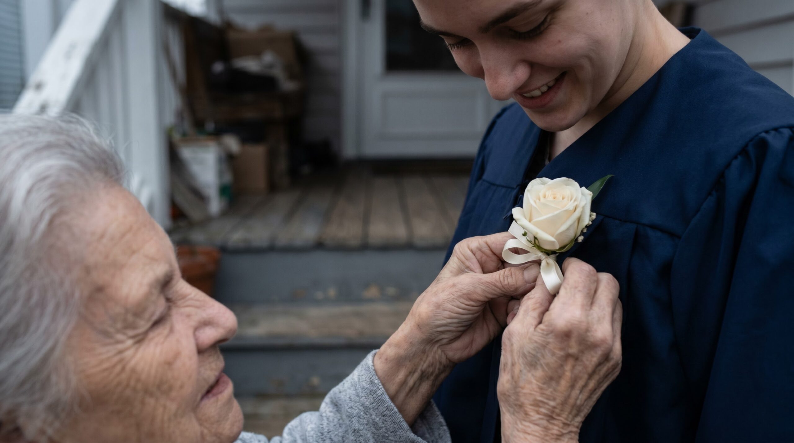 Parent pinning a small corsage onto a graduate's gown before the ceremony