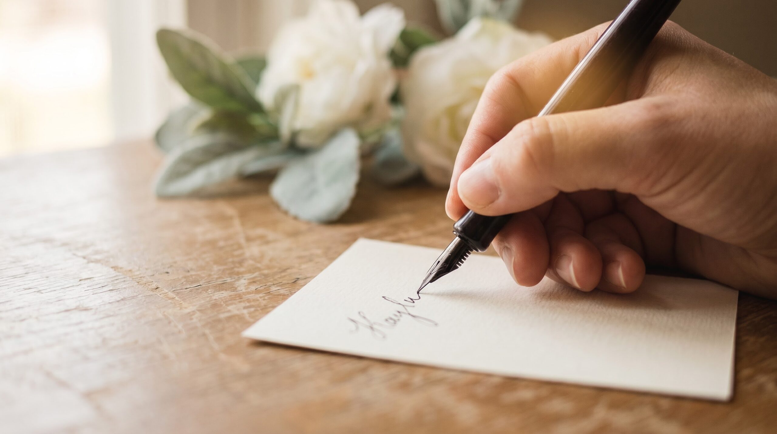A hand signing a sympathy card with a full first and last name