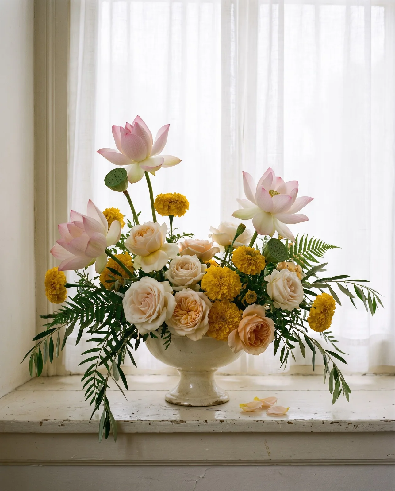 Footed bowl centerpiece with lotus, roses, and marigold blooms