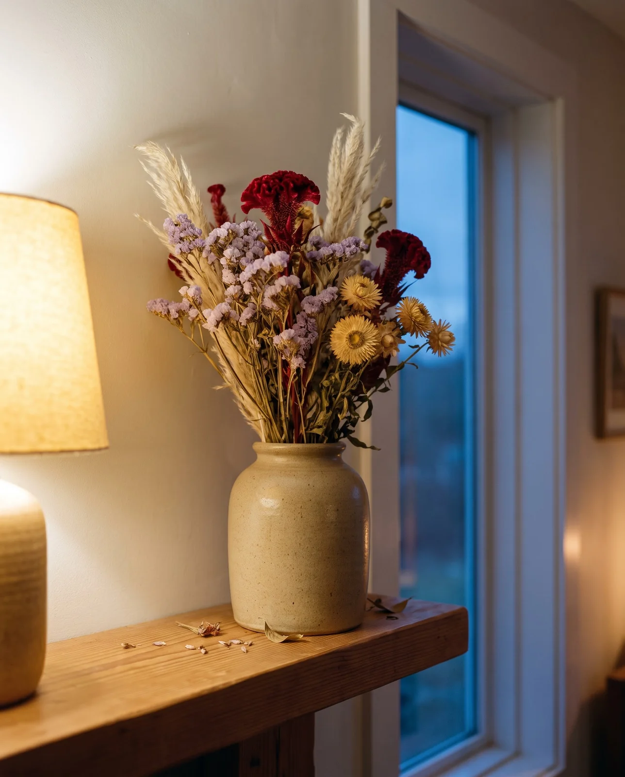 Dried flower arrangement in a stoneware vase on a living-room mantel