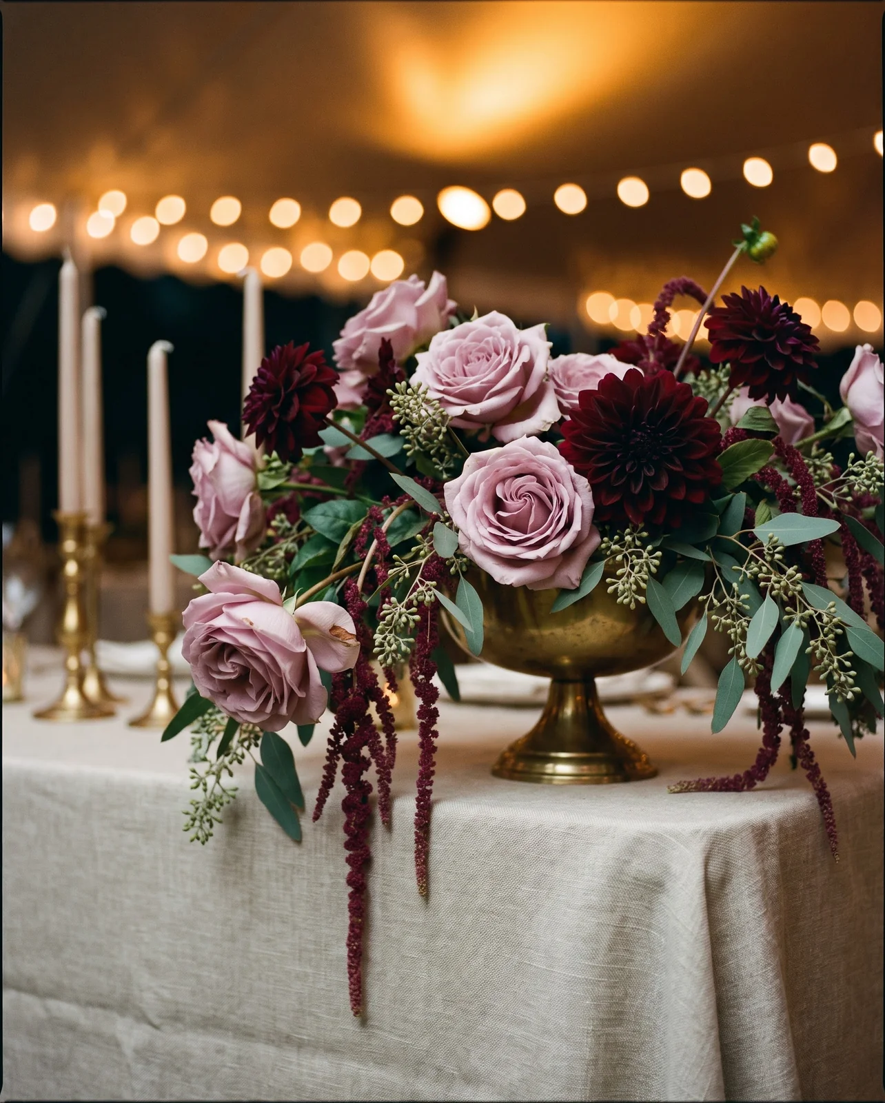 Cascading garden rose and dahlia centerpiece on reception table under string lights