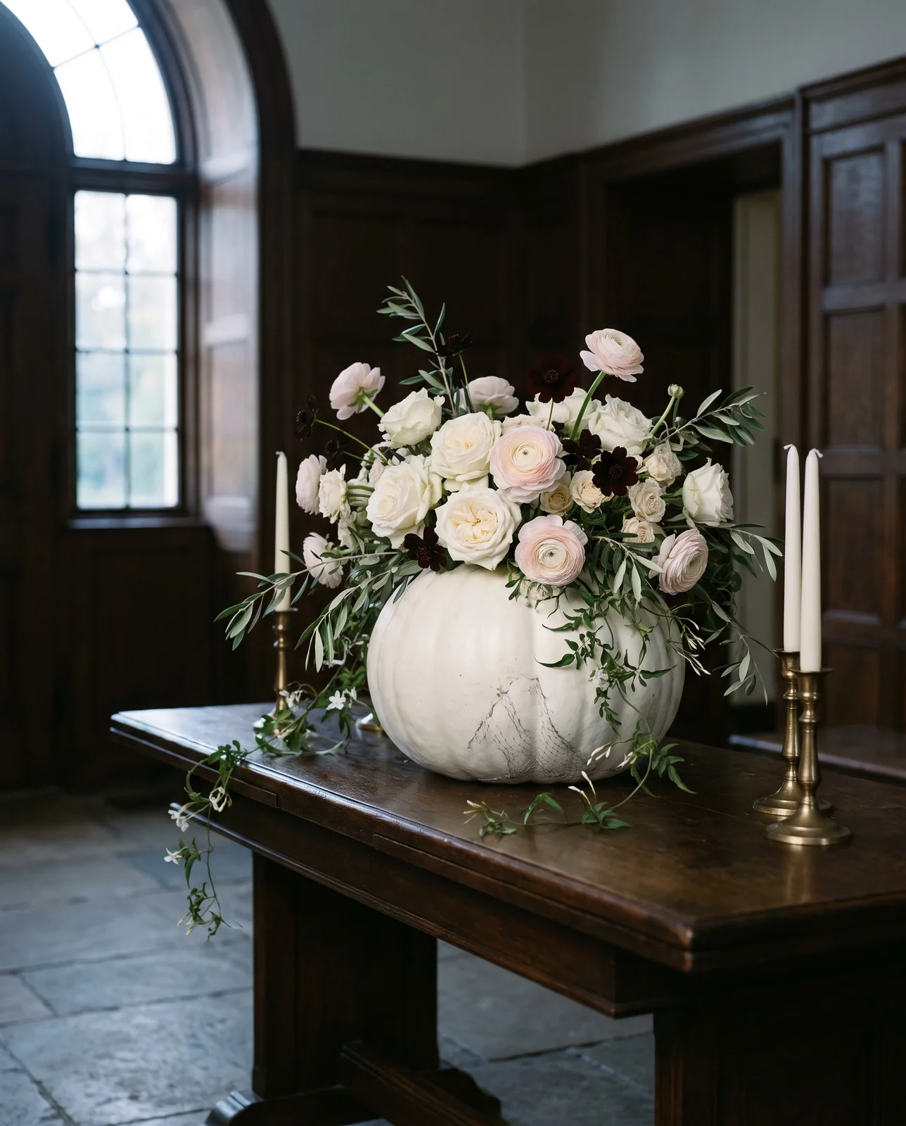 White pumpkin arrangement with roses and ranunculus on entryway console table.
