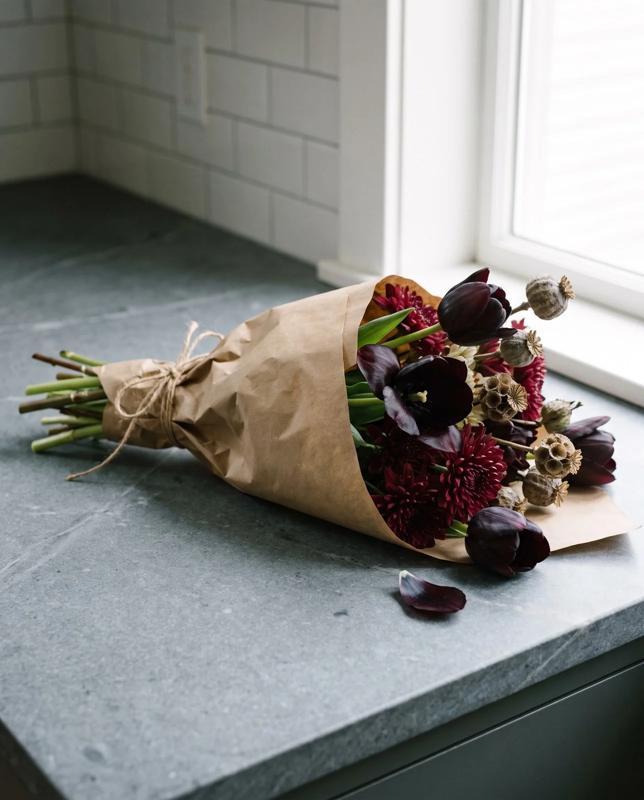 Seasonal bouquet of dark tulips and mums wrapped in kraft paper.