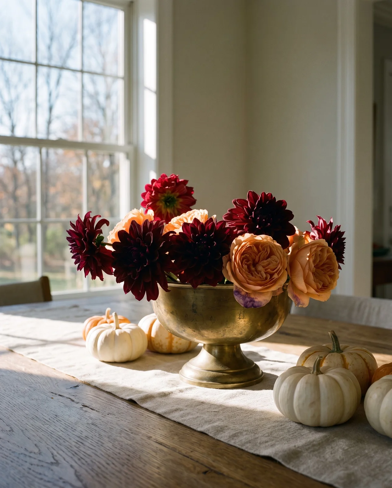 Low brass bowl Thanksgiving centerpiece with burgundy dahlias and mini pumpkins